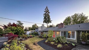 A residential house with a well-maintained garden, a driveway, and a neighboring camper.