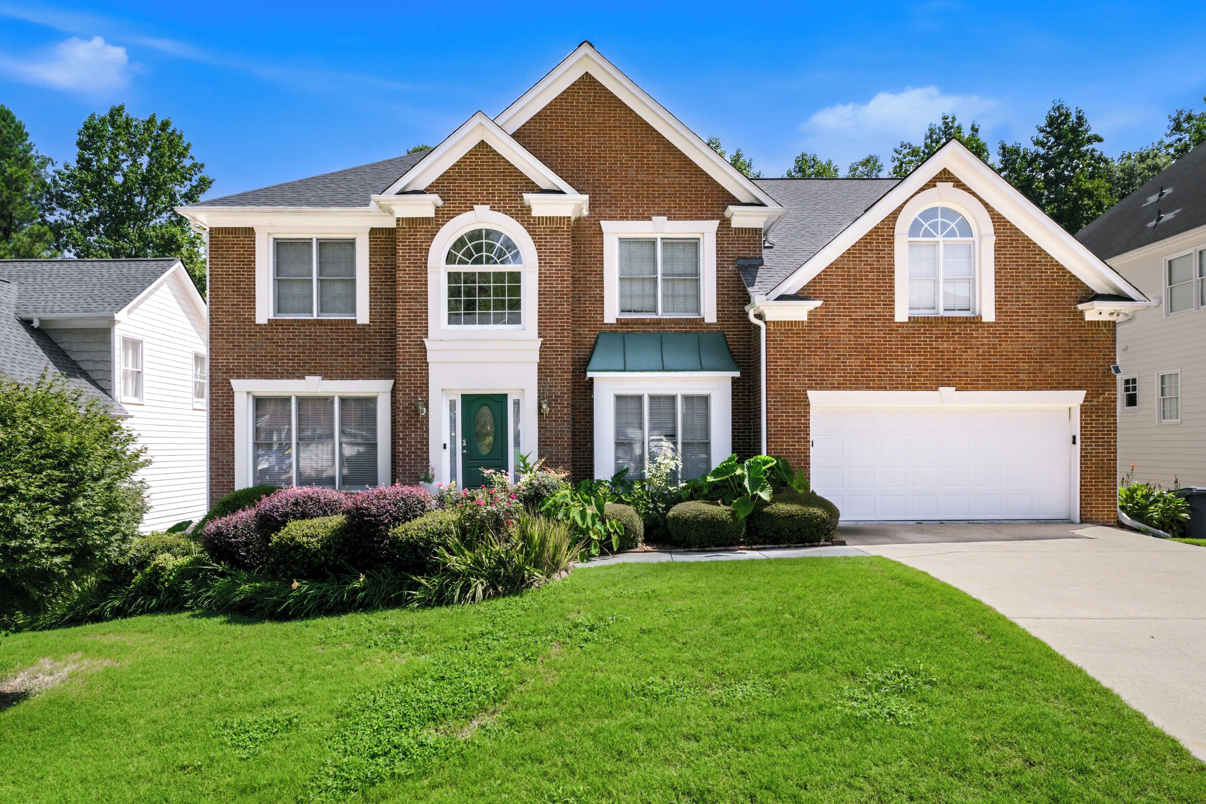 A two-story house with a garage, a front porch, and a well-maintained lawn.