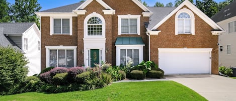 A two-story house with a garage, a front porch, and a well-maintained lawn.