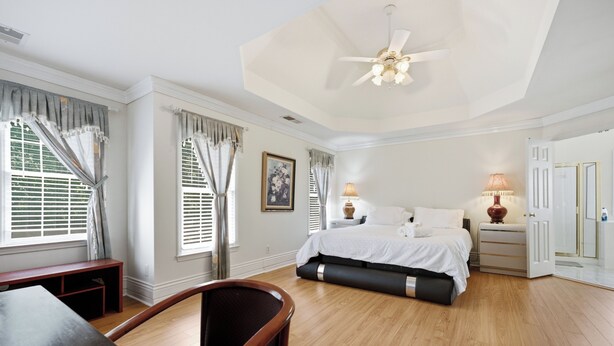 Habitación de hotel con cama, mesitas de noche, escritorio, silla, ventilador de techo y ventana con cortinas.