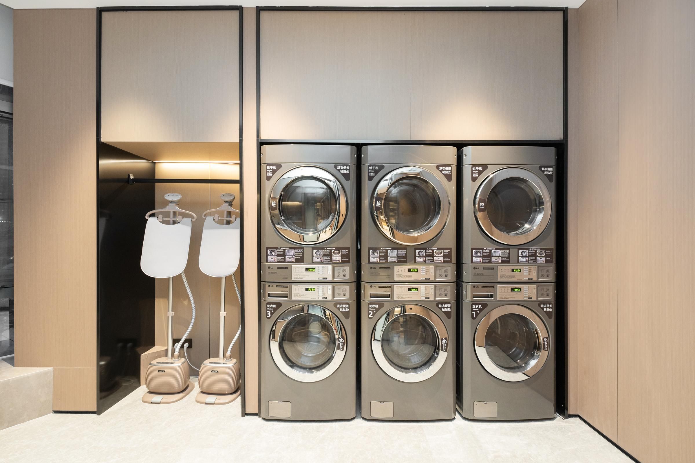 A modern laundry facility with four stacked washing machines and two dryers.