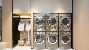A modern laundry facility with four stacked washing machines and two dryers.