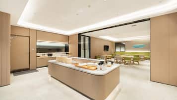 A modern kitchen with a central island, built-in appliances, and a dining area with green chairs.