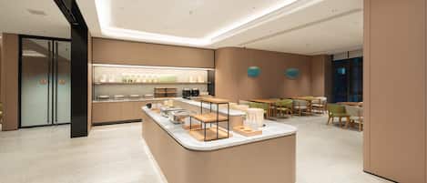 Un hall d’hôtel moderne avec un îlot central, un espace salon et un comptoir d’accueil.