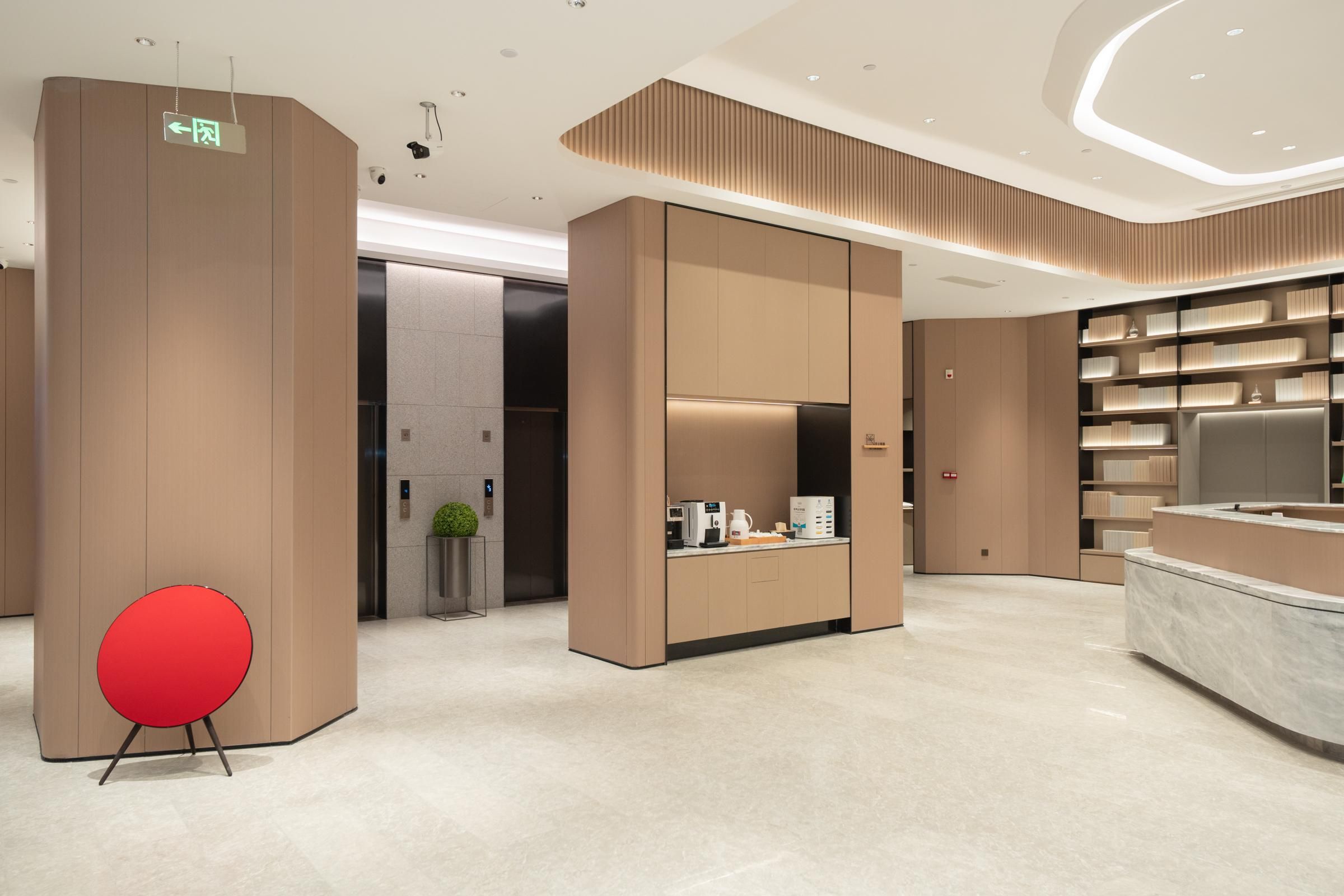 Un vestíbulo moderno con una mesa de recepción, una silla roja y una estación de café.