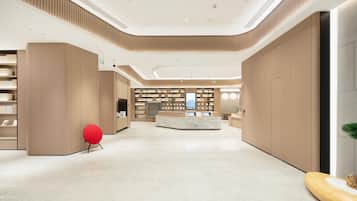 Um lobby moderno com uma recepção central, estantes de livros e uma cadeira vermelha.
