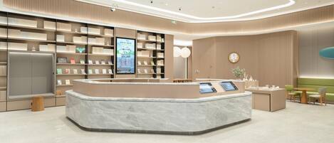 A modern reception area with a marble counter, bookshelves, and a digital information kiosk.