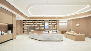 A modern hotel lobby with a central reception desk, a large digital display, and a seating area with tables and chairs. - Ji Hotel Guangzhou Panyu Chimelong Wanbo (Guangzhou)