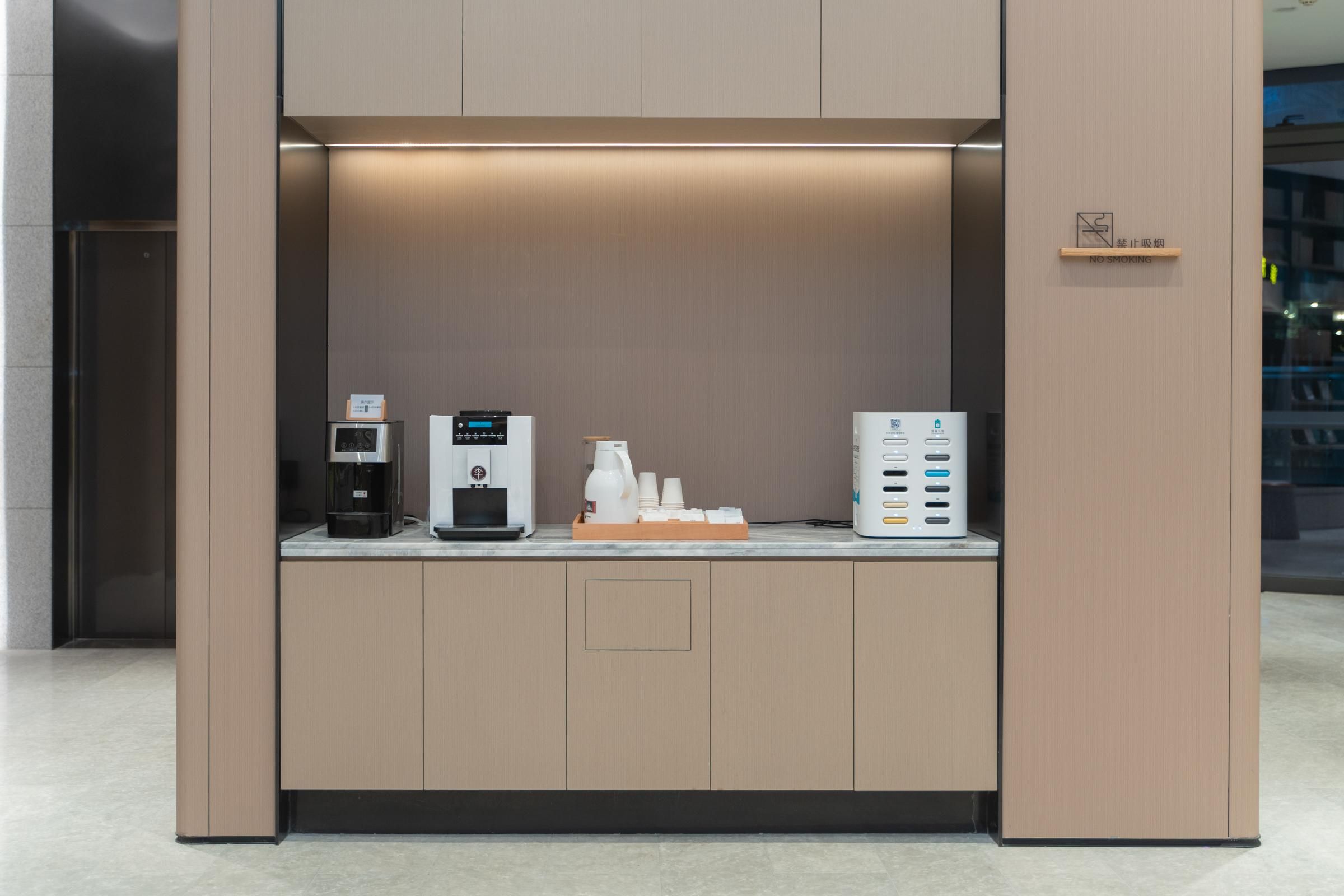 Een moderne koffiehoek met een koffieapparaat, een waterdispenser en een koffiemachine.