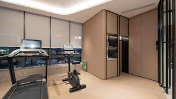 Een moderne hotelkamer met een loopband, een hometrainer en een groot raam met uitzicht op de stad.
