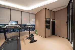 Et moderne hotelværelse med et løbebånd, motionscykel og et stort vindue med udsigt over byen.