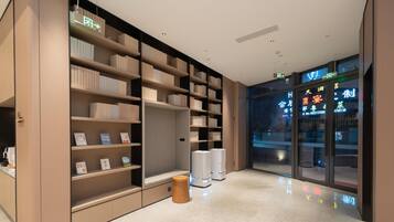 A modern library with bookshelves, a reading area, and a glass wall with signage.