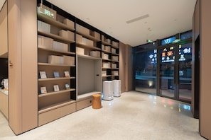 A modern library with bookshelves, a reading area, and a glass wall with signage.