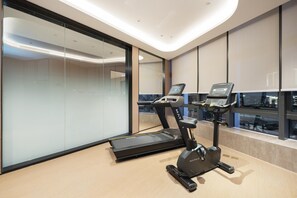 Un gimnasio moderno con cinta de correr y elíptica, ventanas amplias y un diseño minimalista.