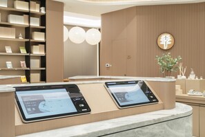 A modern reception desk with digital displays, a wooden reception area, and a wall-mounted sign. - Ji Hotel Guangzhou Panyu Chimelong Wanbo (Guangzhou)