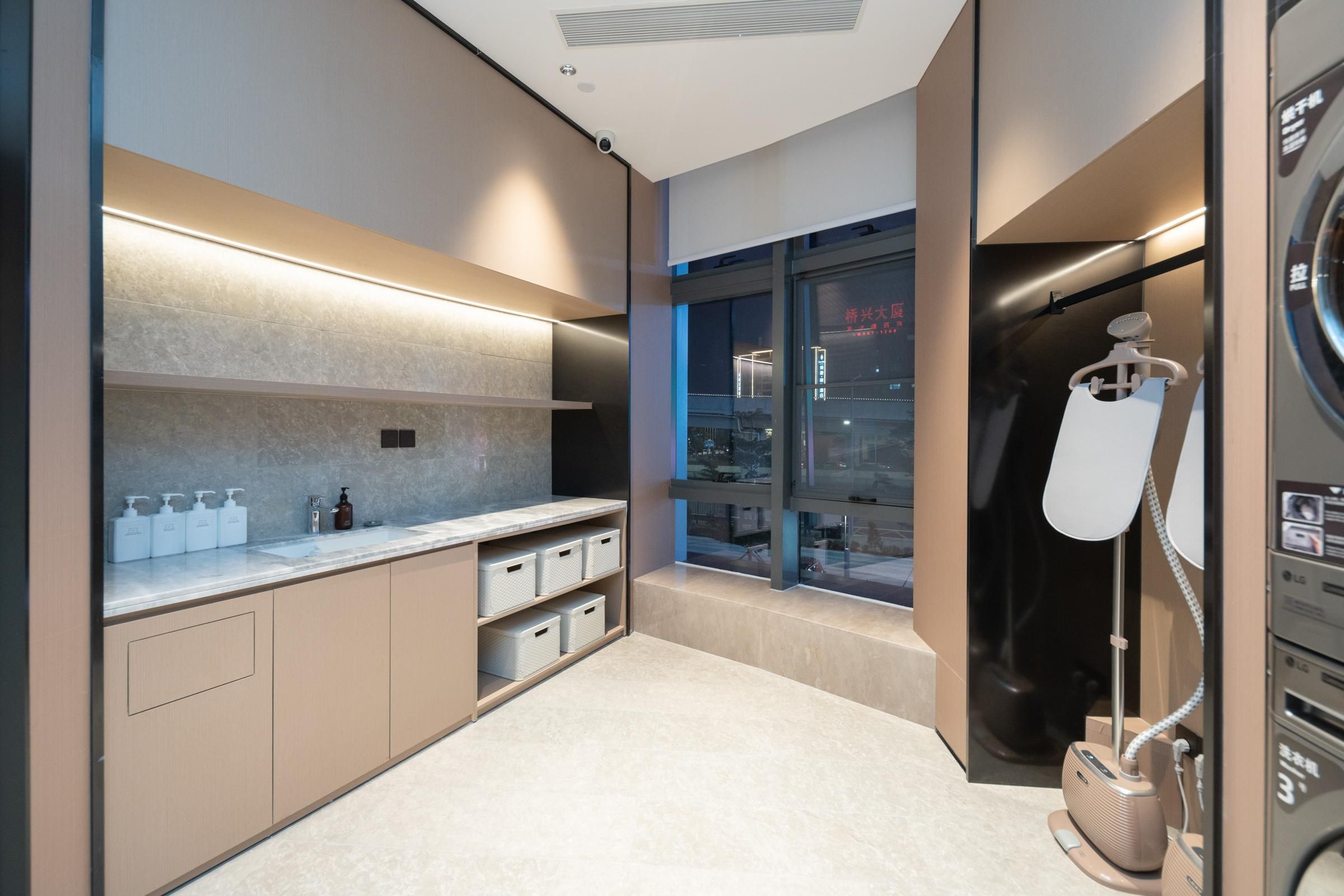 A modern bathroom with a large mirror, a sink with soap dispensers, and a towel rack.