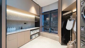 A modern bathroom with a large mirror, a sink with soap dispensers, and a towel rack.