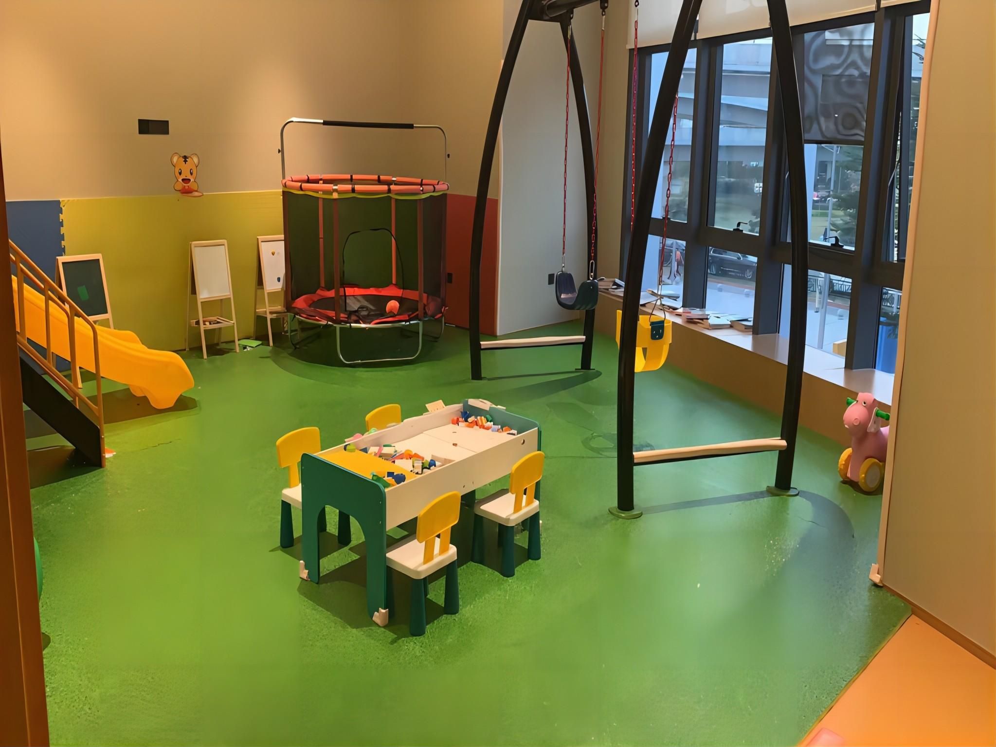 A children's playroom with a trampoline, play table, and toys.