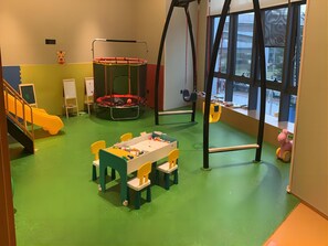 Ein Kinderspielzimmer mit Trampolin, Spieltisch und Spielzeug.