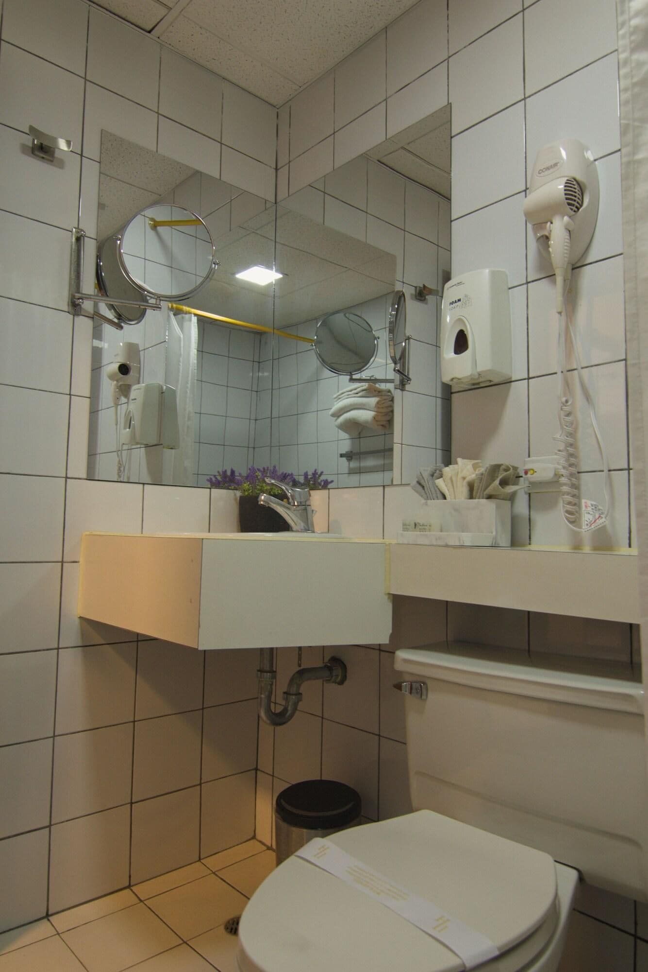 A bathroom with a toilet, sink, mirror, and hairdryer.