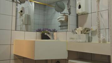 A bathroom with a toilet, sink, mirror, and hairdryer.