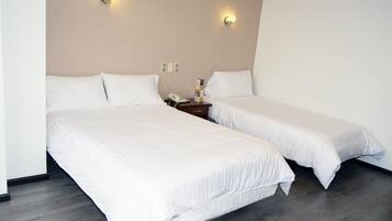 Une chambre d’hôtel avec deux lits simples, une table de chevet avec une lampe et un téléphone fixé au mur.