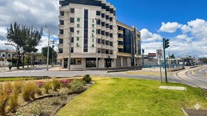 A modern hotel with a multi-story structure, a prominent entrance, and a well-maintained lawn area. - Hotel Italia Cuenca (Cuenca)