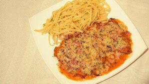 A plate of spaghetti with a meat-based dish, possibly chicken parmesan, on a white plate. - Hotel Italia Cuenca (Cuenca)