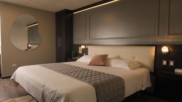 Una camera d'albergo con un letto grande, uno specchio rotondo e luci a parete.