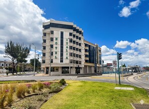 A modern hotel with a multi-story structure, a prominent entrance, and a well-maintained lawn area. - Hotel Italia Cuenca (Cuenca)