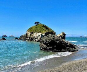 Una costa rocciosa con acque cristalline blu e una piccola isola erbosa.