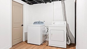 A laundry room with two white washing machines, a drying rack, and a door. - Completely Renovated Home in St. Charles, Missouri (Saint Charles)