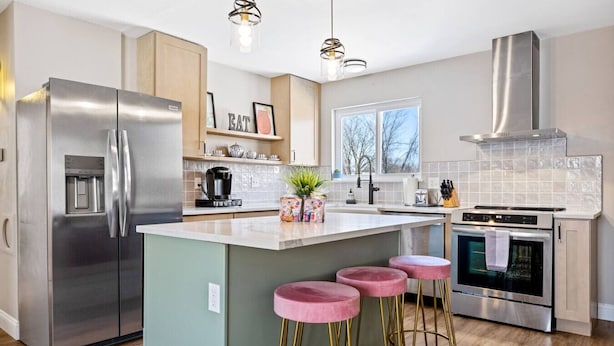 A modern kitchen with a stainless steel refrigerator, an island with pink stools, a gas stove, and a large window. - Completely Renovated Home in St. Charles, Missouri (Saint Charles)