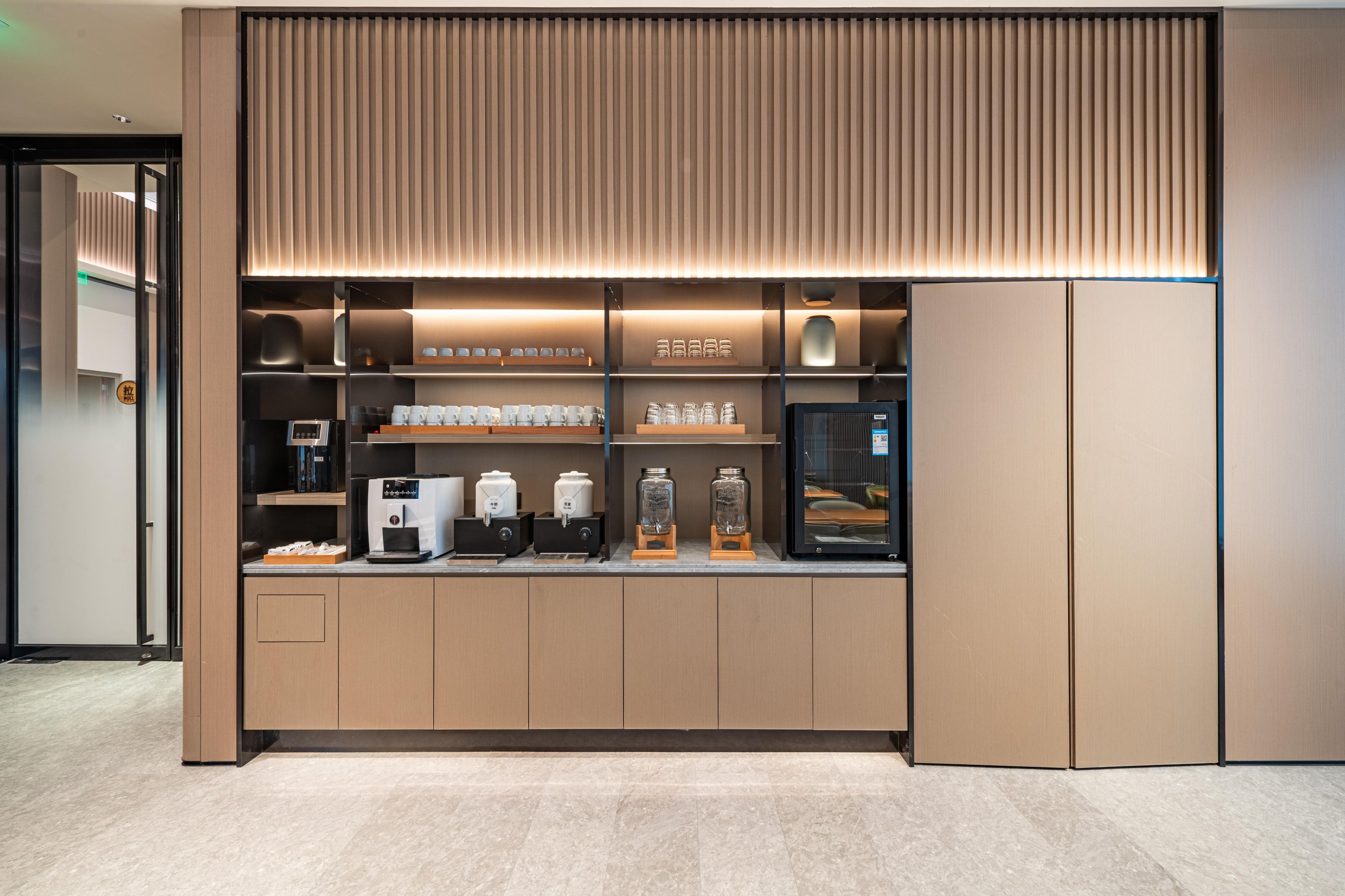 Uma estação de café moderna com máquina de expresso embutida, moedor de café e variedade de xícaras e potes.