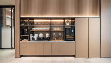 Uma estação de café moderna com máquina de expresso embutida, moedor de café e variedade de xícaras e potes.