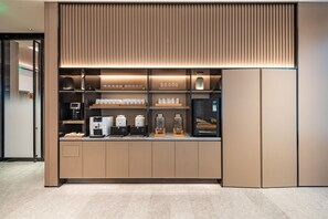 A modern coffee station with a built-in espresso machine, a coffee grinder, and a selection of coffee cups and jars. - Ji Hotel Guangzhou Panyu Shiqiao Metro Station (Guangzhou)