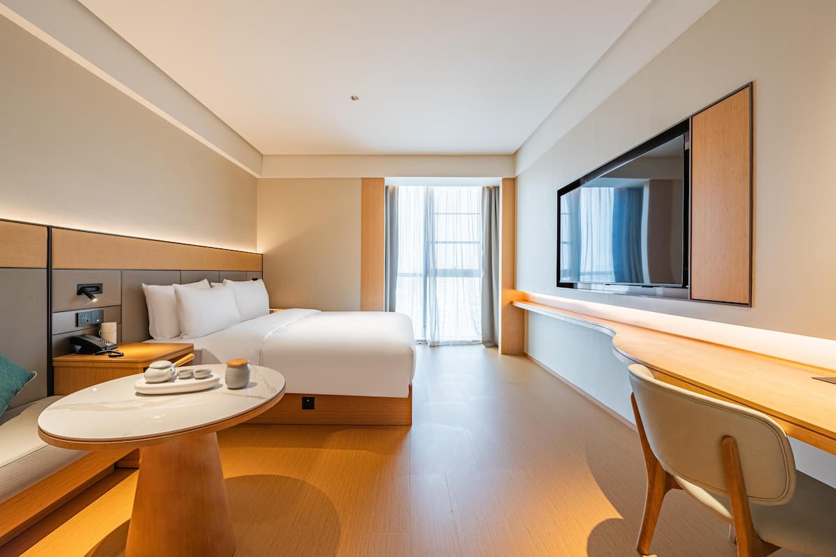 Ein modernes Hotelzimmer mit einem Bett, einem Nachttisch und einem Schreibtisch mit Stuhl.