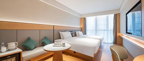 A modern hotel room with a large bed, a sofa, a small table, and a TV.