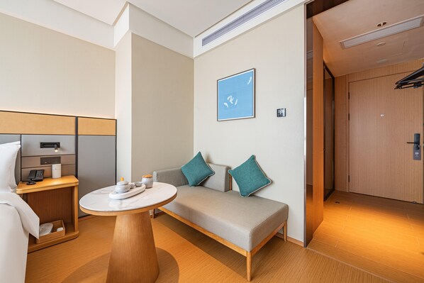 A modern hotel room with a sofa, a small table, a bedside table with a lamp, and a wardrobe. - Ji Hotel Guangzhou Panyu Shiqiao Metro Station (Guangzhou)