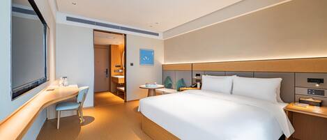 Ein modernes Hotelzimmer mit einem großen Bett, einem Schreibtisch und einem Sessel.