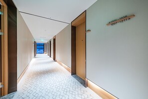 A modern hotel corridor with wooden doors, numbered room signs, and a patterned floor. - Ji Hotel Guangzhou Panyu Shiqiao Metro Station (Guangzhou)
