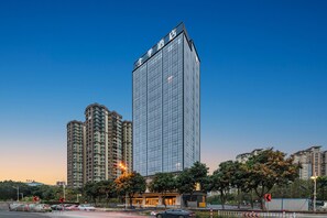 Ein Hochhaus-Hotel mit moderner Glasfassade an einer Stadtkreuzung, umgeben von weiteren Hochhäusern.