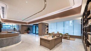 Un moderno vestíbulo de hotel con un mostrador de recepción curvo, una zona de estar central y grandes ventanales que ofrecen vistas de la ciudad.