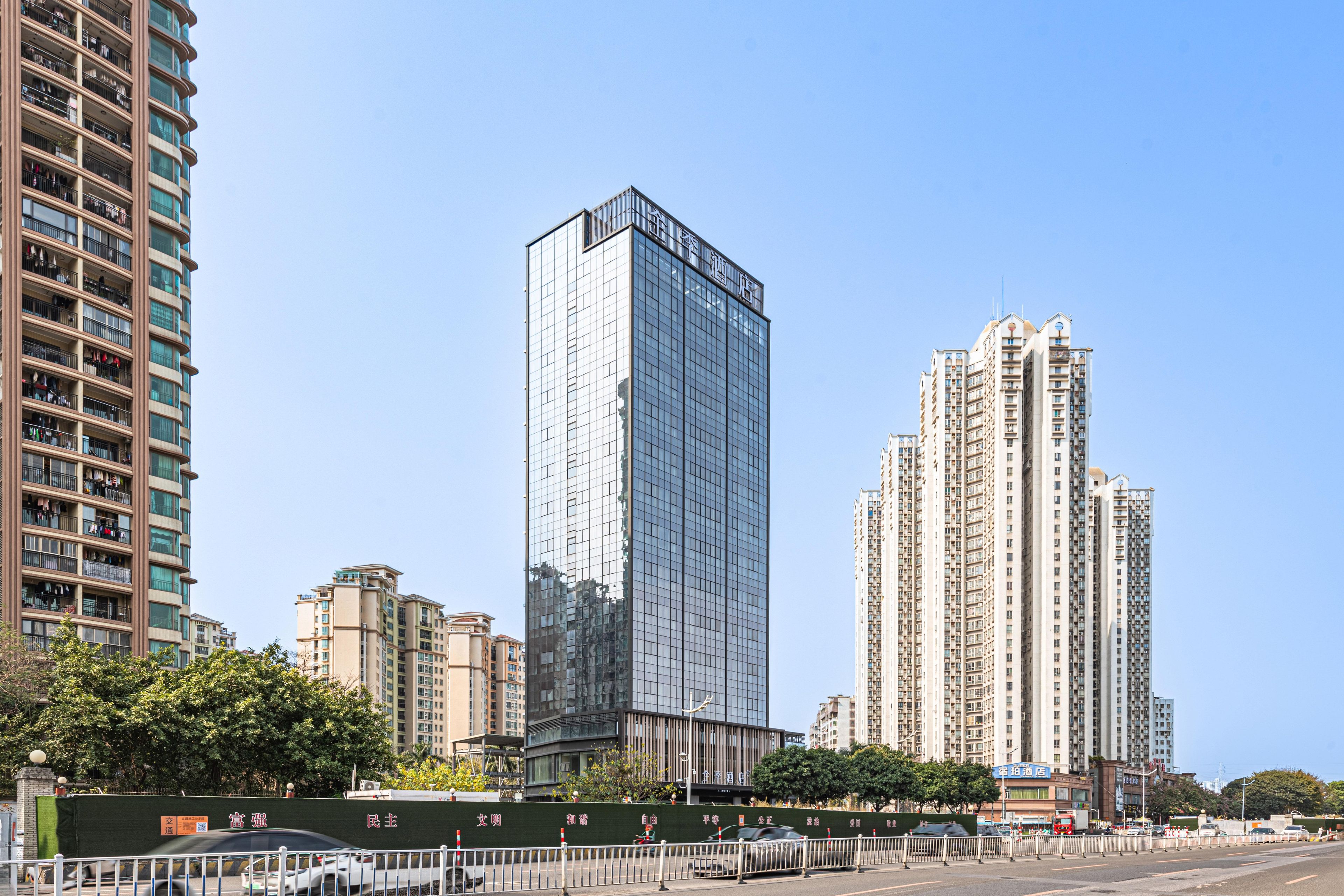 A high-rise hotel with a modern glass facade, surrounded by other tall residential buildings.