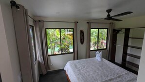 Une chambre à coucher avec un lit, un ventilateur de plafond et des fenêtres avec des rideaux.