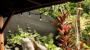 Un hamac installé sous une zone abritée, avec un jardin de rochers et diverses plantes.