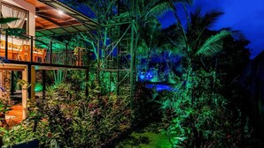 A modern house with a glass balcony overlooking a lush garden at night. - Entire Property, Great Location,Daily Housekeeping,Concierge (Quepos, Manuel Antonio)