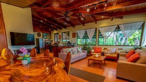 Amplia sala de estar con una mesa de comedor de madera, sofás y televisión.