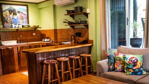 Una cocina con taburetes de madera, una barra y un sofá con cojines de colores.