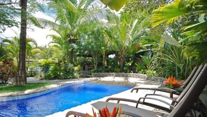 Piscina rodeada de exuberante vegetación y palmeras.